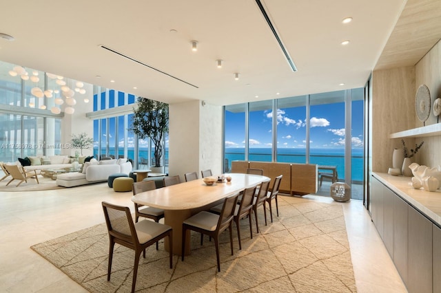 dining room with expansive windows, a towering ceiling, recessed lighting, and a water view