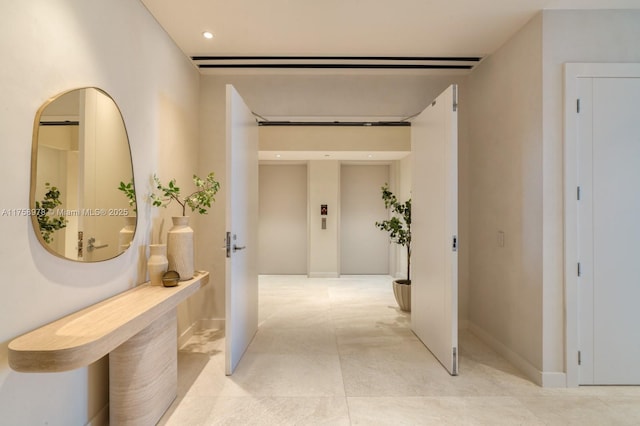 hall featuring baseboards, recessed lighting, and elevator