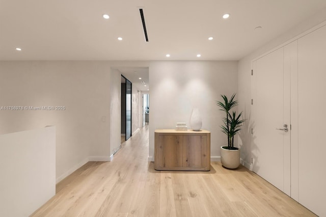 hall featuring baseboards, light wood-type flooring, and recessed lighting