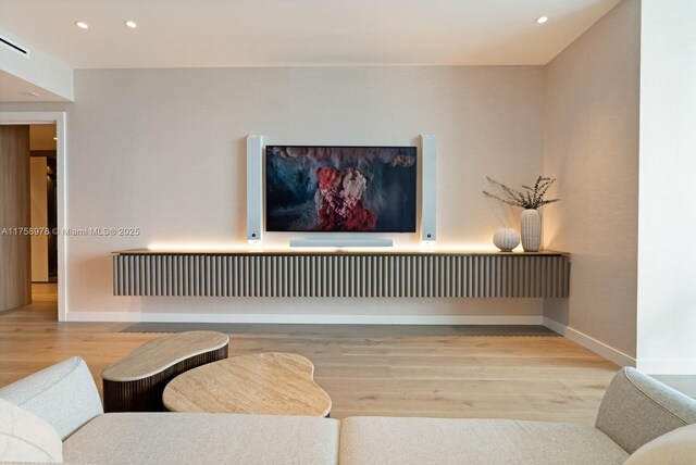 living area with baseboards, wood finished floors, and recessed lighting