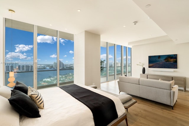bedroom featuring a wall of windows, wood finished floors, and access to outside