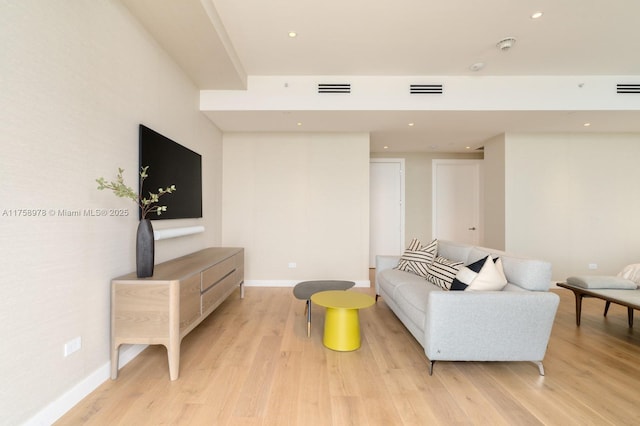 living room with visible vents, light wood-style flooring, and baseboards