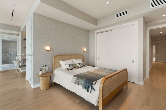 bedroom featuring light wood-type flooring, baseboards, visible vents, and a closet