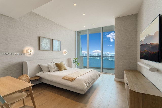 bedroom featuring recessed lighting, light wood finished floors, access to exterior, a water view, and expansive windows