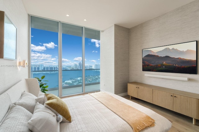 bedroom with floor to ceiling windows, wood finished floors, access to exterior, and recessed lighting