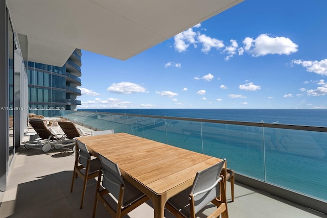 balcony featuring outdoor dining area and a water view