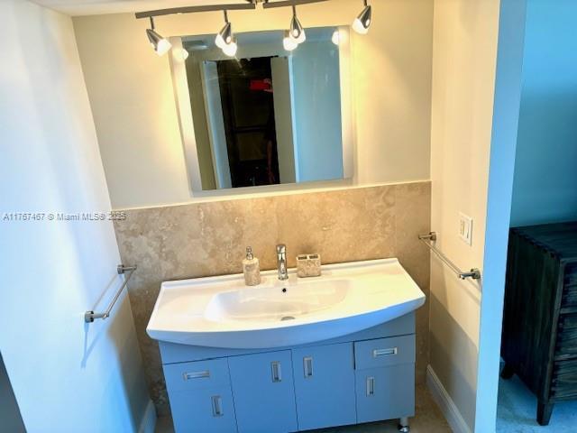 10410 S Ocean Dr Unit 504, Jensen Beach, FL 34957 - bathroom featuring vanity, tile walls, and a wainscoted wall