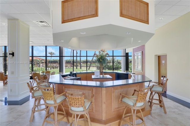 10410 S Ocean Dr Unit 504, Jensen Beach, FL 34957 - kitchen featuring a large island with sink, a drop ceiling, dark countertops, a towering ceiling, and light tile patterned floors