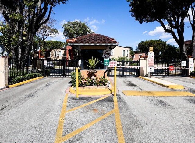 10772 N Kendall Dr Unit G5, Miami, FL 33176 - view of asphalt road featuring a gated entry, a gate, traffic signs, and curbs