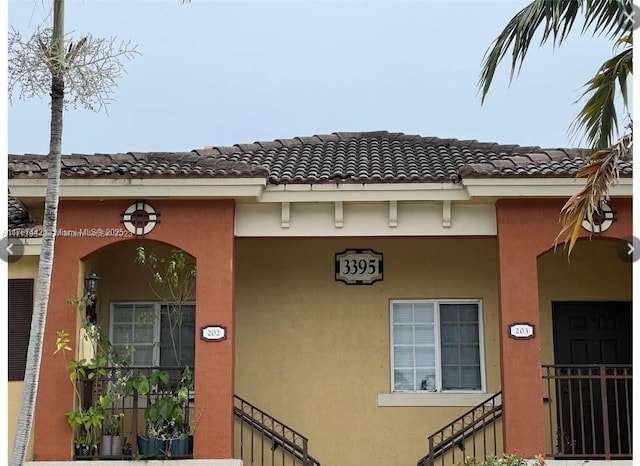 property entrance with stucco siding and a tile roof
