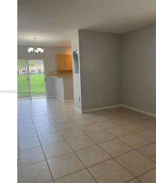 spare room featuring light tile patterned floors, baseboards, and a notable chandelier