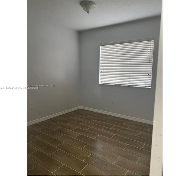 empty room with dark wood finished floors and baseboards