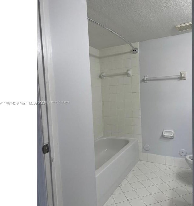 bathroom featuring tile patterned floors, toilet, tub / shower combination, and a textured ceiling