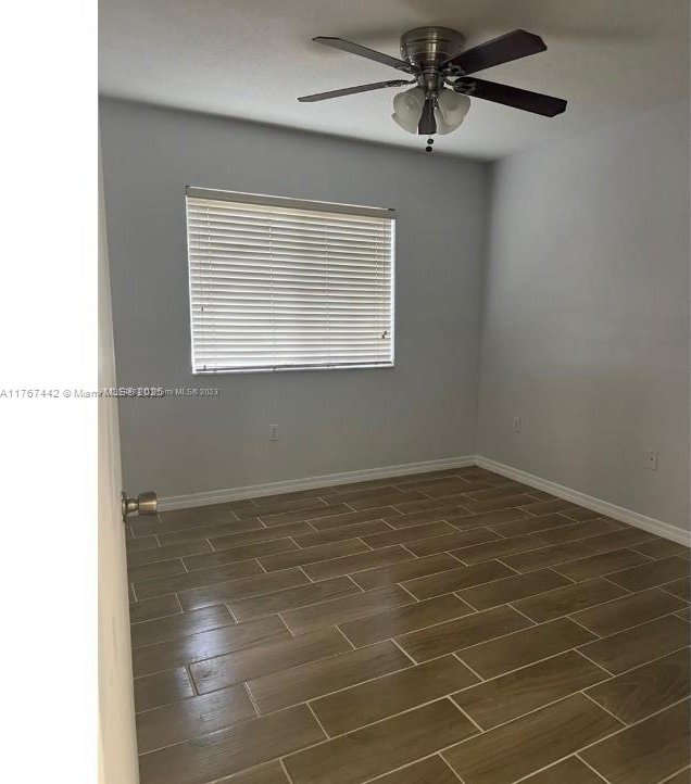 spare room featuring a ceiling fan, baseboards, and wood tiled floor