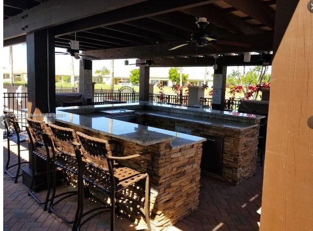 view of patio / terrace featuring outdoor wet bar, exterior kitchen, a ceiling fan, and fence