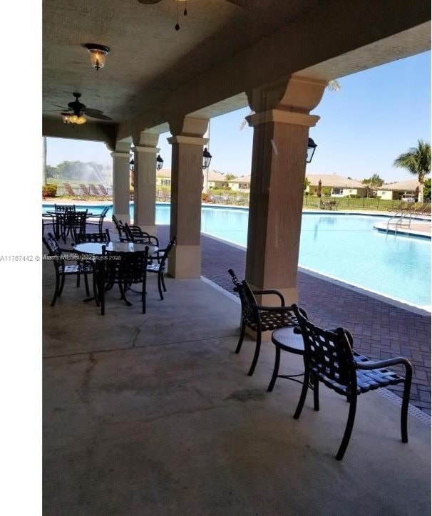 view of patio with a community pool and ceiling fan