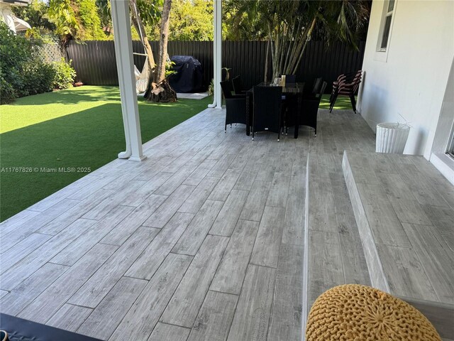 wooden terrace featuring a fenced backyard, outdoor dining space, and a yard