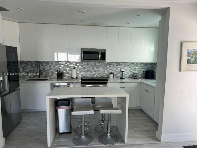 kitchen with visible vents, modern cabinets, a sink, and appliances with stainless steel finishes