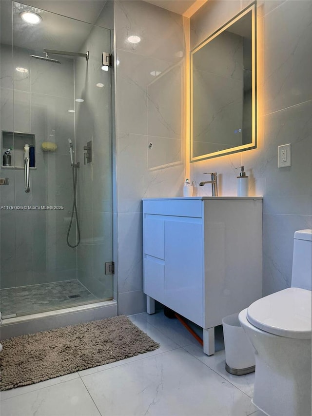 full bathroom featuring marble finish floor, vanity, a stall shower, and tile walls