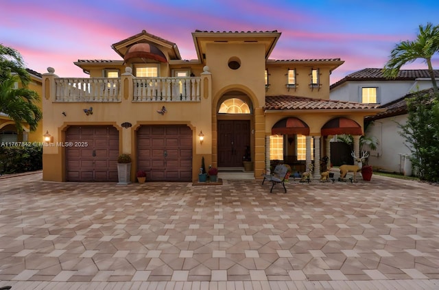 view of front of property featuring stucco siding, decorative driveway, and a balcony