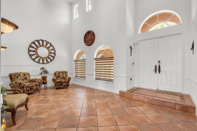 foyer entrance featuring tile patterned floors, a high ceiling, and baseboards