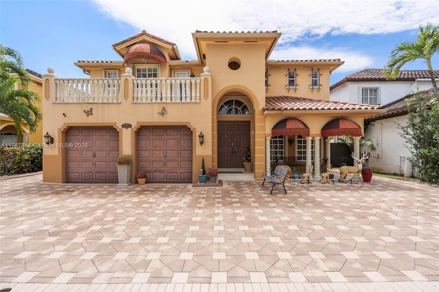mediterranean / spanish-style home with stucco siding, a balcony, and a tiled roof
