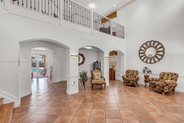living area featuring baseboards, arched walkways, and light tile patterned flooring