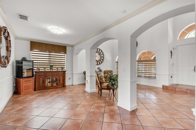 foyer with crown molding, light tile patterned flooring, baseboards, and visible vents