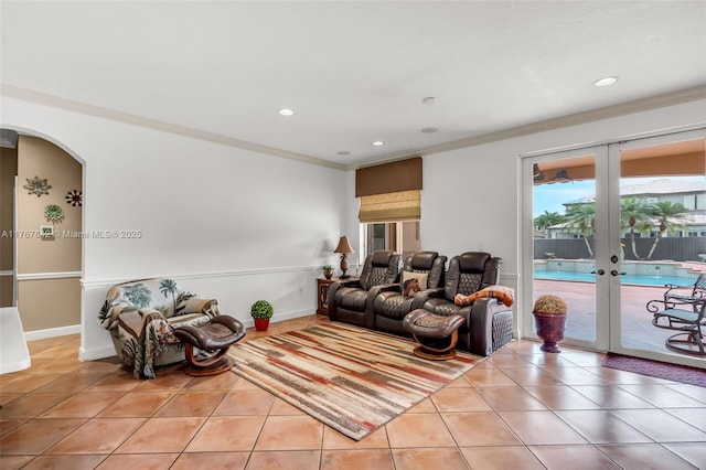 living area featuring french doors, arched walkways, crown molding, light tile patterned floors, and baseboards