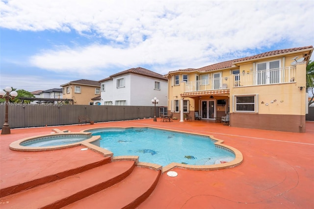 view of swimming pool with french doors, a patio, a pool with connected hot tub, and fence