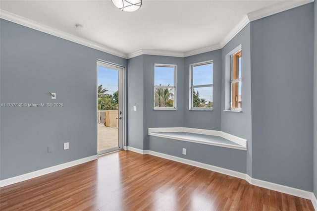 spare room with wood finished floors, baseboards, and ornamental molding