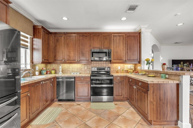 kitchen with visible vents, backsplash, appliances with stainless steel finishes, a peninsula, and a sink