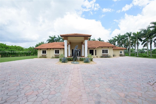 back of property with stucco siding, curved driveway, and a tiled roof