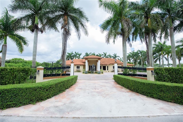 mediterranean / spanish-style home with stucco siding, fence, and a gate