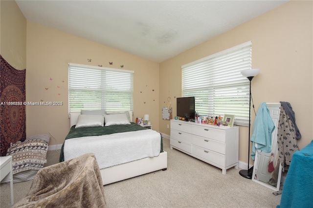 bedroom with lofted ceiling, baseboards, and light carpet