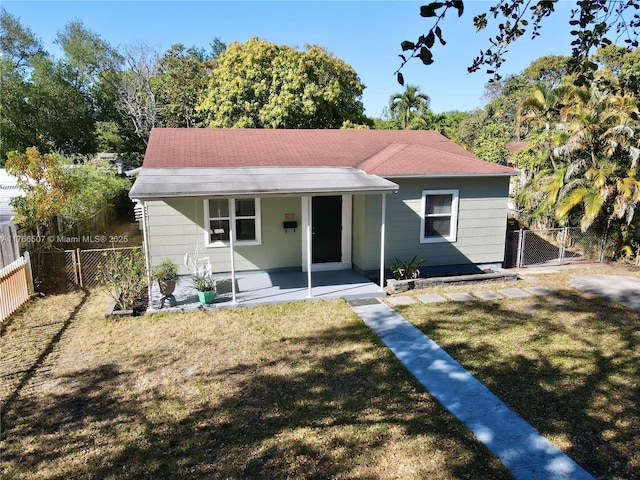 back of house featuring a gate, fence, a porch, a shingled roof, and a lawn