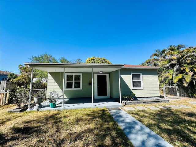 bungalow-style house with a front lawn, a gate, fence, and a patio area