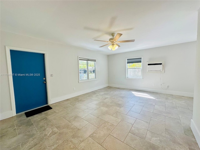 unfurnished room with an AC wall unit, a ceiling fan, and baseboards