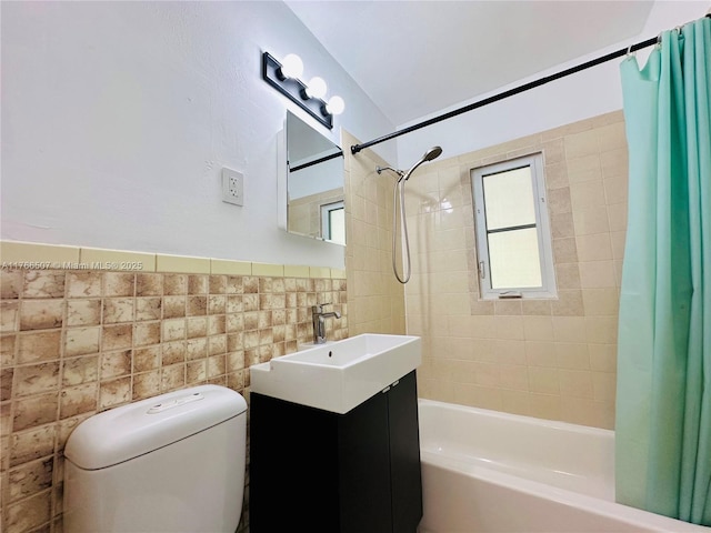 full bathroom featuring shower / bath combo with shower curtain, toilet, tile walls, wainscoting, and vanity