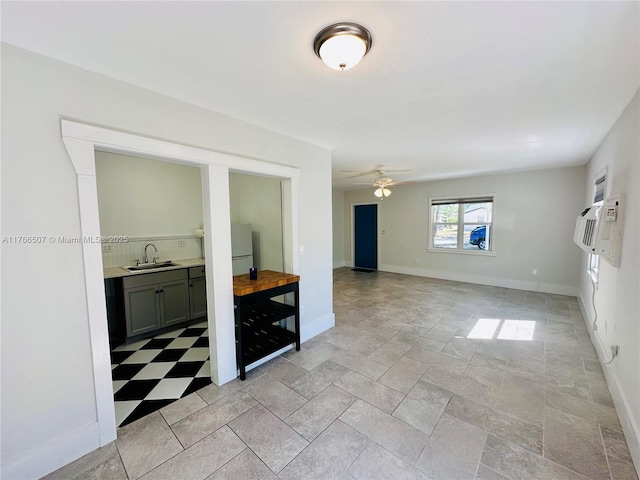 spare room featuring baseboards, a ceiling fan, and a sink