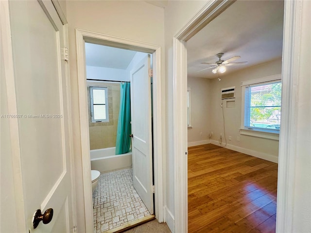 hall with wood finished floors, baseboards, and a wall mounted air conditioner