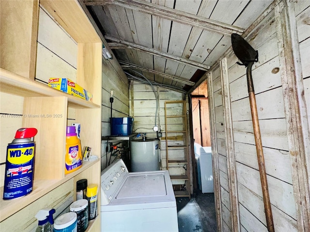 clothes washing area with gas water heater, wooden walls, washer / dryer, and laundry area