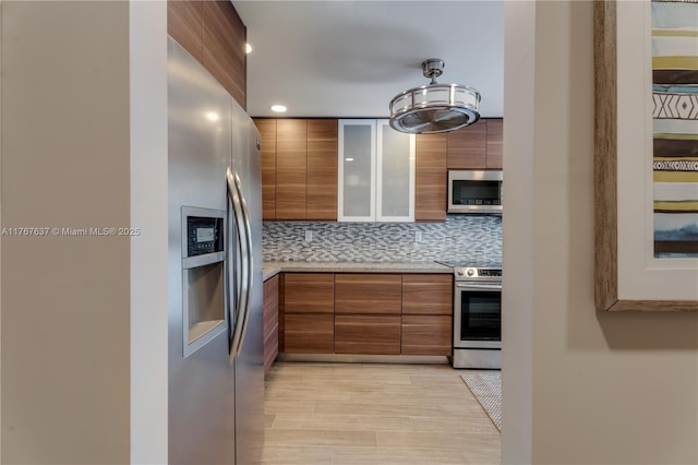 kitchen featuring modern cabinets, brown cabinetry, and appliances with stainless steel finishes