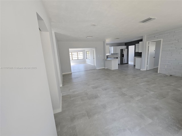 unfurnished living room featuring baseboards, visible vents, and concrete flooring