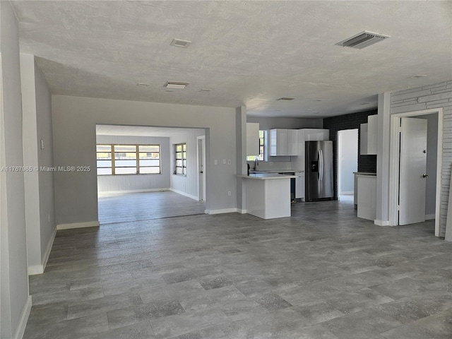 unfurnished living room with visible vents, a textured ceiling, baseboards, and a sink