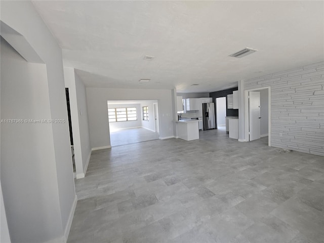 unfurnished living room featuring visible vents and baseboards