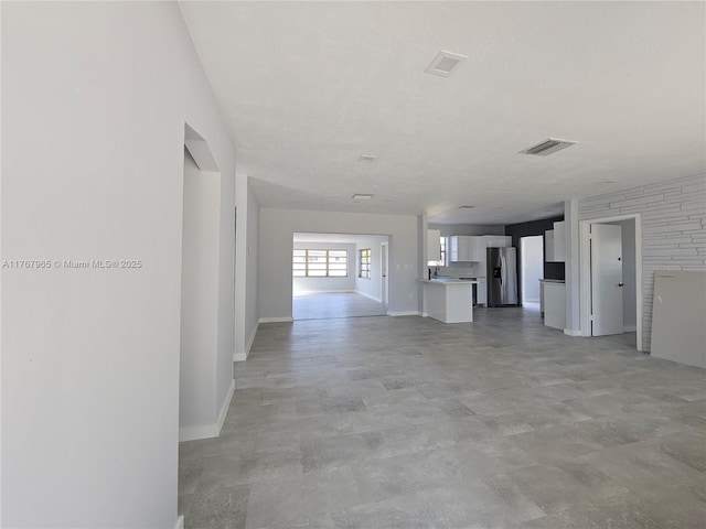 unfurnished living room featuring baseboards and visible vents