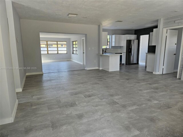 unfurnished living room with visible vents, baseboards, and a sink