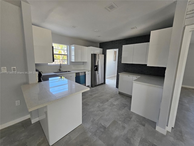 kitchen with modern cabinets, a sink, a peninsula, stainless steel fridge with ice dispenser, and dishwasher