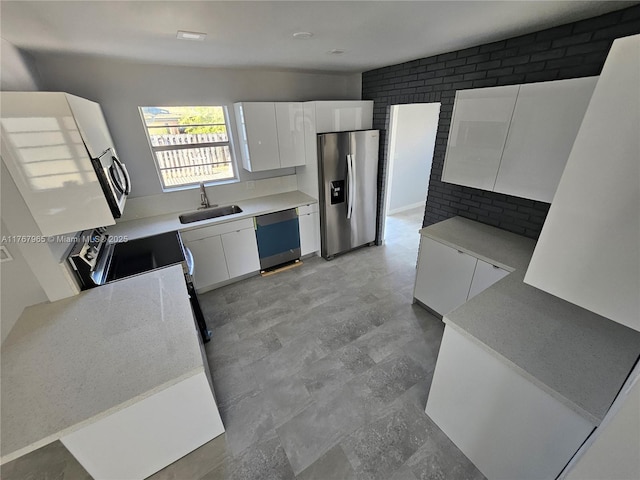 kitchen with dishwashing machine, brick wall, a sink, stainless steel refrigerator with ice dispenser, and white cabinetry
